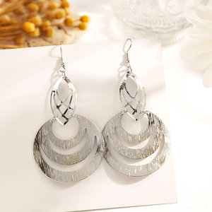 Gros plan de boucles d'oreilles argentées avec feuille ajourée et design géométrique