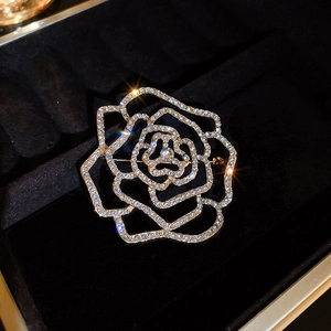 Macro detail of a sparkling gold-tone hollow camellia brooch with rhinestones
