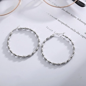 Minimalist silver bamboo-style stainless steel large hoop earrings on a vintage paper background