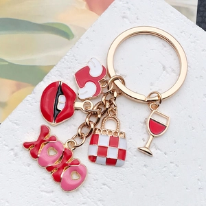 Detailed close-up of golden keychain with red lip, XOXO, and handbag enamel charms