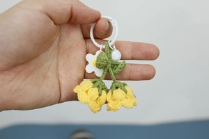 Detail of handmade knit lily of the valley keychain with yellow flowers and green leaves