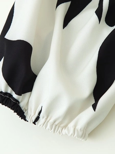 Close-up of elasticated cuff detail on a black and white cow print polyester dress
