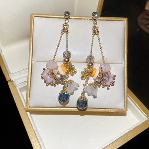 Detailed shot of long gold earrings with crystal beads and blue teardrop in a jewelry box
