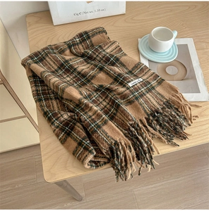 Close-up of vintage brown plaid scarf with tassels on a cozy wooden background