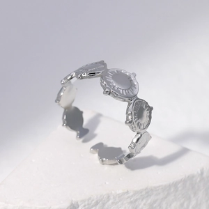 Silver stainless steel open ring with repeating sunburst floral pattern on stone stand