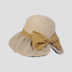 Dettaglio di un cappello da sole elegante in paglia beige con grande fiocco giallo decorativo