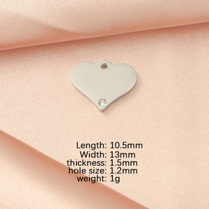 Macro shot of silver heart pendant with crystal detail and dimensions on satin fabric
