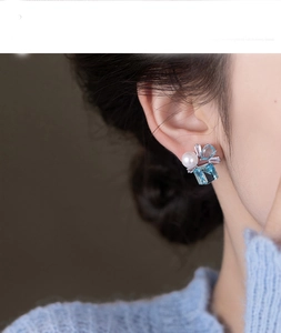 Detail of square blue stone and pearl earring on model with silver pin finish
