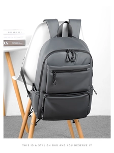 Zaino business grigio minimalista per laptop esposto su una moderna sedia bianca