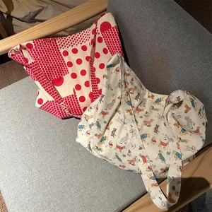 Detail of two canvas tote bags with red polka dots and cartoon dog prints on a grey sofa