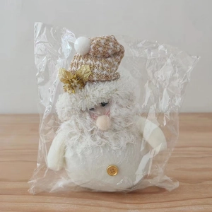Detailed view of plush Christmas gnome doll in white outfit with gold buttons in packaging