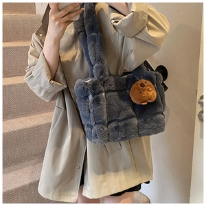 Blue fuzzy shoulder bag with cute bear charm shown on model in cozy interior setting
