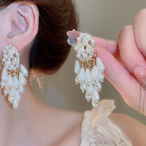 Close-up of elegant pearl tassel earrings with rhinestones on model's ear