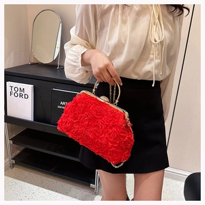 Detail of red 3D rose petal textures and gold metal handle on a luxury evening bag