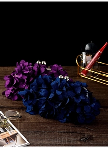 Detailed view of elegant purple and navy evening clutches with 3D floral petals on table