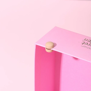 Close-up of magnetic scarf clip in beige attached to a pink gift box for secure closure