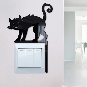 Detail of a black mirror acrylic black cat wall sticker above a white light switch