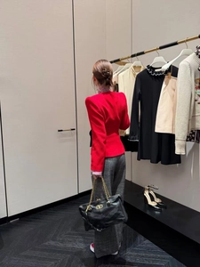 Detail of a red slim coat paired with a black chain bag featuring a gold V-logo
