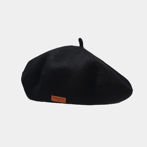 Close-up of black wool beret featuring a vintage brown leather label with LOVE STYLE text