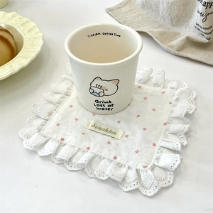 Close-up of white heart lace coaster with floral patterns under a ceramic coffee mug