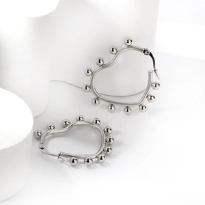 Macro shot of silver heart-shaped stainless steel hoop earrings with bead edge detailing