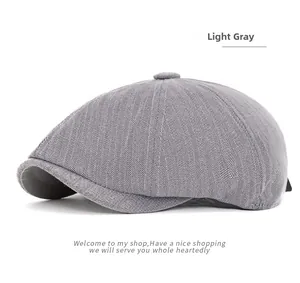 Detail of light gray herringbone newsboy cap featuring fabric texture and top button