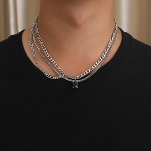 Detail of layered silver Figaro chain with a black rectangular pendant on a model
