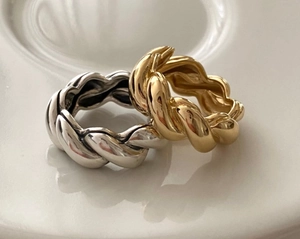 Macro shot of silver and gold braided rings showing the S925 hallmark on a white dish