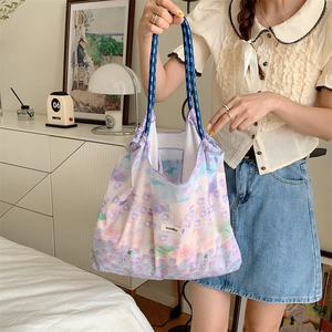 Detail of floral tote bag showing woven rope handles and brand label in home setting