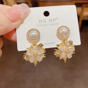 Macro shot of elegant starburst pearl earrings with crystal inlay and gold finish