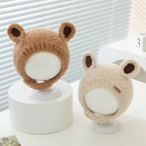 Close-up of plush baby winter hats with cute bear ears and stylish leather fashion labels