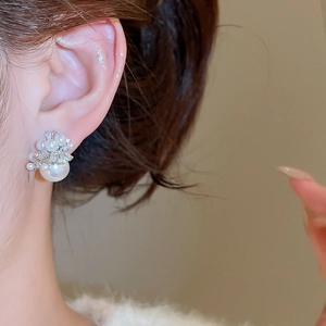 Close-up of pearl and crystal flower stud earring worn on model's ear for elegant look