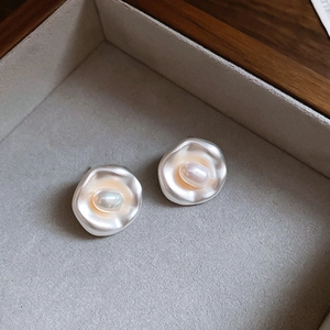 Close-up of silver baroque pearl earrings nestled in a gray velvet jewelry box display