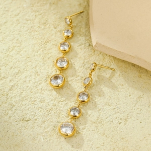 Elegant gold drop earrings with cascading round zircons on stone display stand