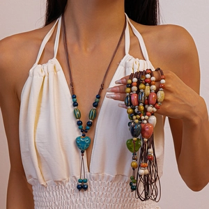 Gros plan de perles en céramique colorées et d'un pendentif en cœur sur un collier tissé main