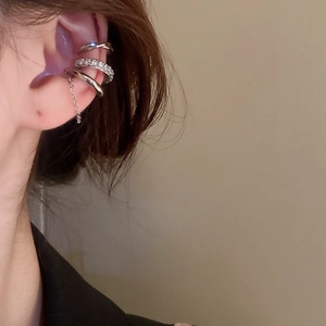 Detail of silver ear cuffs set with cubic zirconia and a delicate chain dangle