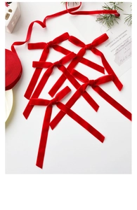 Close-up of red velvet Christmas tree bows with pine needles and decorative card