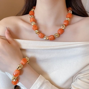 Close-up of orange acrylic beads and gold irregular metal accents on a stylish bracelet