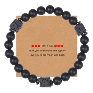 Detail of matte black stone bead bracelet with lava rock on brown gift message card