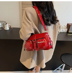 Detail of red punk-style shoulder bag with silver eyelets and multiple pockets on strap