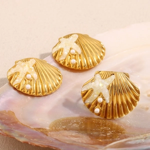 Macro detail of 18K gold plated starfish and shell earrings featuring pearls on a sea shell