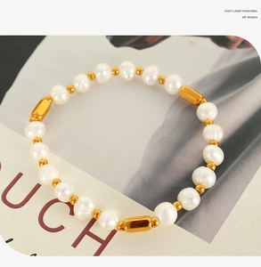 Detailed view of elegant freshwater pearl bracelet with shiny gold metallic beads on a magazine