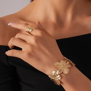 Close-up of golden flower relief bangle and ring set with brushed metal texture