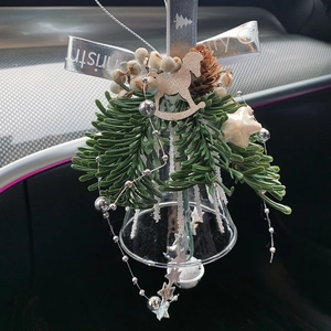 Christmas glass bell ornament with pine branches and wooden horse hanging in car interior