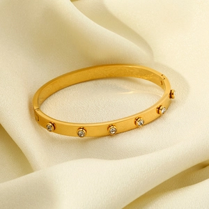 Elegant gold-plated stainless steel bangle featuring zircon stones on cream silk fabric