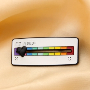 Macro view of slider heart on rainbow mood enamel pin over gold silk background