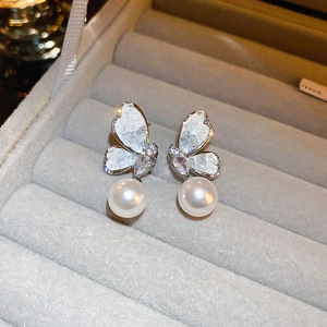 Macro shot of silver butterfly earrings with zircons and white pearls in a jewelry box