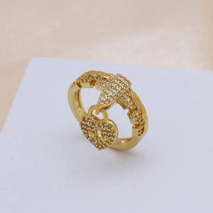 Detail view of a gold-plated ring featuring a heart lock and key pendant with zircons