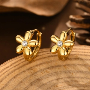 Detail of gold flower hoop earrings with white round stone on natural wood background