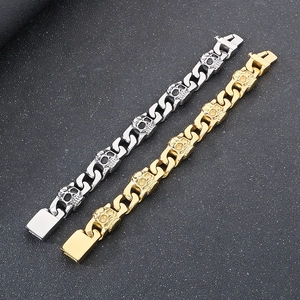 Detail showing gold and silver Cuban link bracelets with skull charms on a textured surface